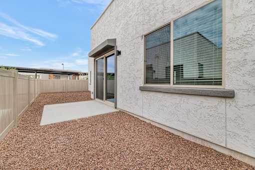 A modern house with a glass door and a gravel driveway at Marketside Villas at Verrado, Buckeye, AZ