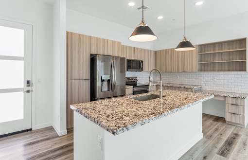 A kitchen with a granite countertop and a sink at Marketside Villas at Verrado, Buckeye, AZ
