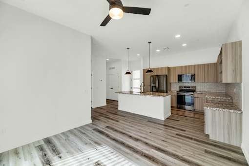 A modern kitchen with wooden floors and a ceiling fan at Marketside Villas at Verrado, Buckeye, AZ