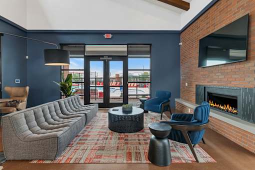 A living room with a grey couch, a blue chair, a fireplace and a red carpet at Marketside Villas at Verrado, Buckeye, AZ
