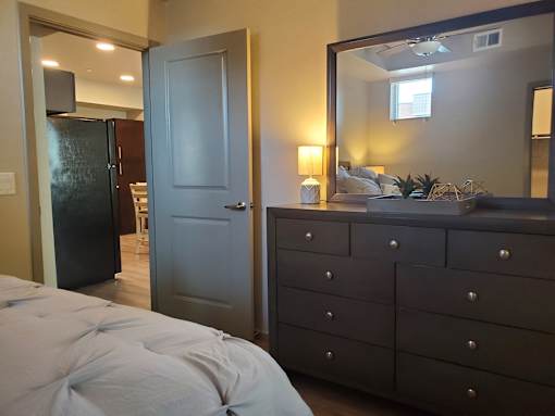 Bedroom with dresser and view to kitchen at Pinon Lofts Apartments, Arizona