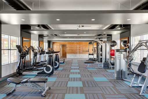 A gym with a variety of equipment including treadmills, weights, and exercise machines at Denim Scottsdale, Scottsdale, AZ