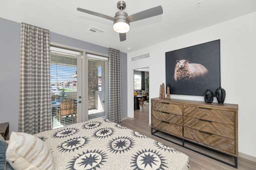 A bedroom with a bed, a dresser, and a ceiling fan.