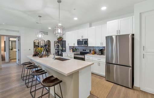 A modern kitchen with a white island and stainless steel appliances.