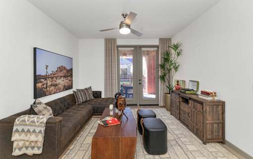 A living room with a brown couch, a coffee table, and a painting on the wall.