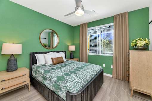 A bedroom with a bed, nightstand, and a mirror on the wall.