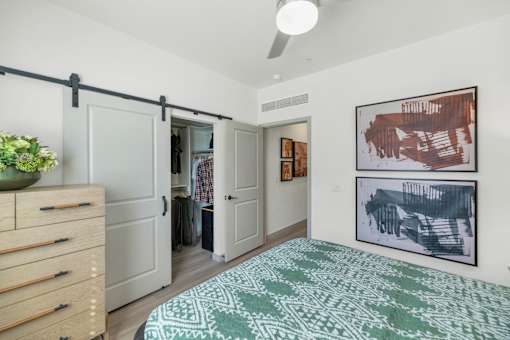 A bedroom with a bed, dresser, and artwork on the wall.