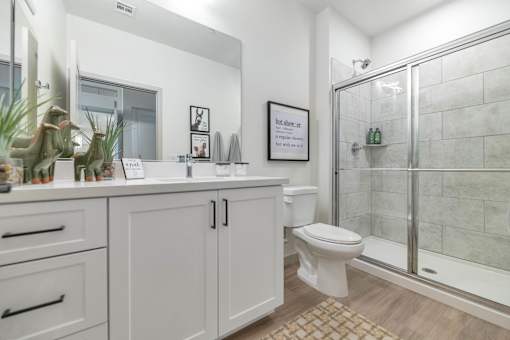 A white bathroom with a toilet, sink, and mirror.