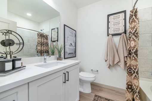 A bathroom with a white toilet, sink, and a framed picture on the wall.