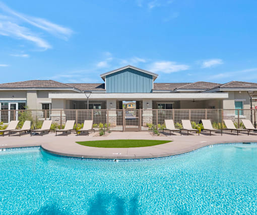 A swimming pool in front of a building with a blue sky in the background.