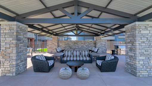 A patio with a stone pillar and a black couch.