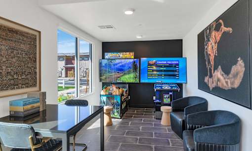 A room with a black sofa, a table with a keyboard and a chair.