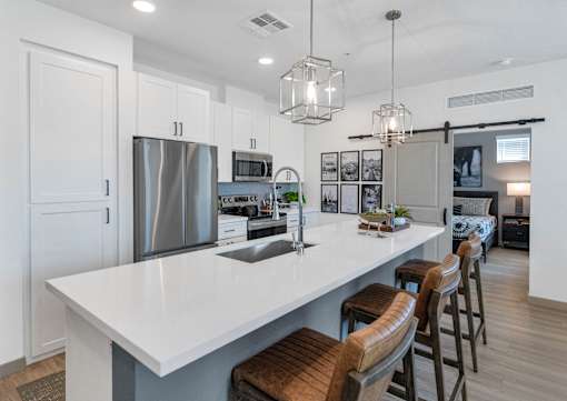 A modern kitchen with a large island and stools.