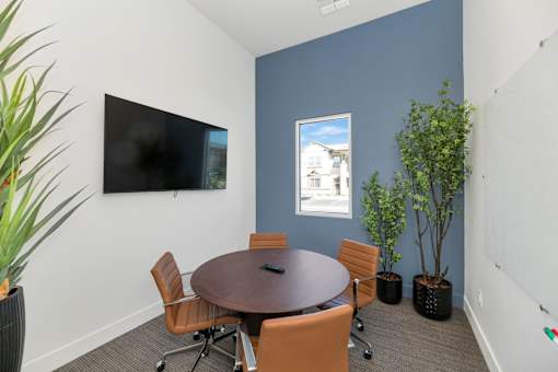 A conference room with a table, chairs, and a television.