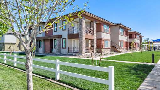 A white picket fence in front of a row of apartment buildings.