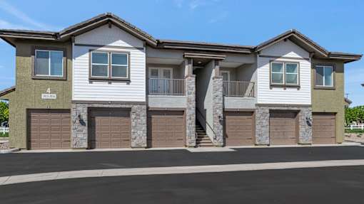 A modern two-story house with stone pillars and garage doors.