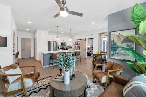 A living room with a ceiling fan and a coffee table with a vase on it.