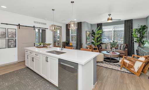 A modern kitchen with a large island and a dining area with a table and chairs.