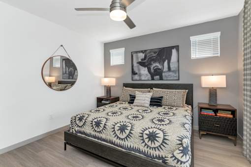 A bedroom with a bed, two lamps, and a ceiling fan.