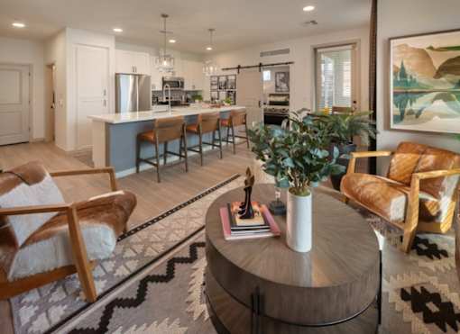 A modern living room with a kitchen in the background.