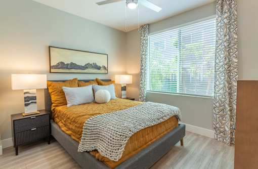 A bedroom with a bed, two lamps, and a painting on the wall.