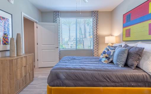 A bedroom with a bed, a dresser, and a painting on the wall.