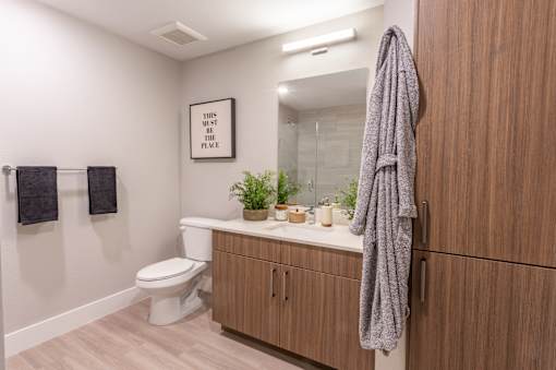 A bathroom with a toilet, a sink, a mirror, and a towel hanging on the door.