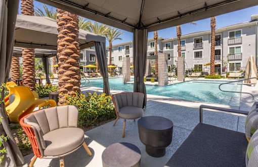 A patio with a table and chairs overlooking a pool.
