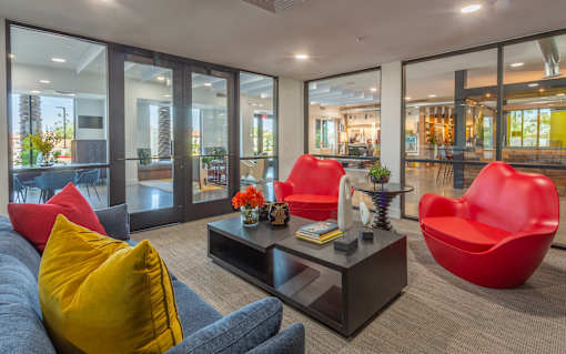 A modern living room with a grey sofa, red chairs and a coffee table.