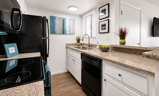 A kitchen with a black fridge and white cabinets.