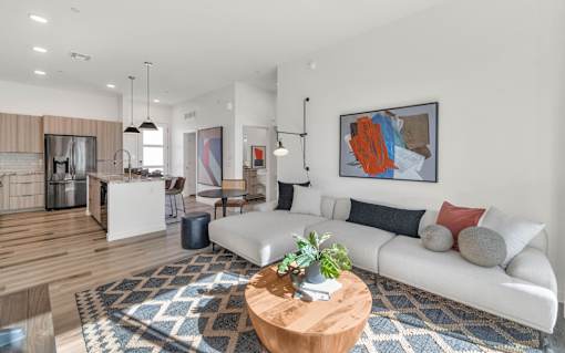 A modern living room with a white sofa, a wooden coffee table, and a large abstract painting on the wall.at Marketside Villas at Verrado, Buckeye, 85396
