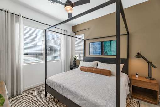 A bedroom with a four poster bed and a ceiling fan.at Marketside Villas at Verrado, Buckeye, AZ