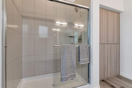A bathroom with a glass shower door and a towel hanging on the side.at Marketside Villas at Verrado, Buckeye, 85396
