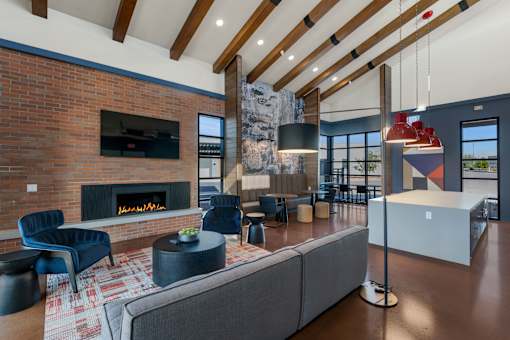 A modern living room with a brick fireplace and a grey sofa.at Marketside Villas at Verrado, Buckeye, AZ, 85396