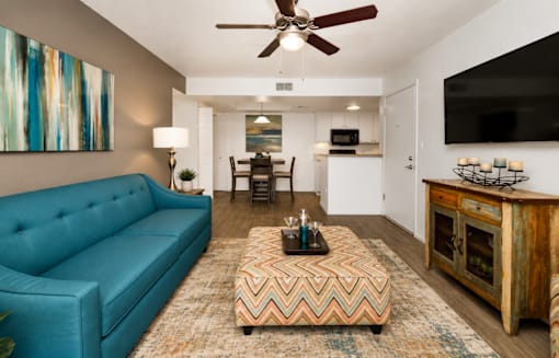 A living room with a blue couch and a chevron patterned ottoman.