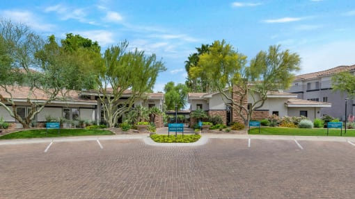 an empty parking lot in front of a building with trees at Montage at Pecos Ranch Apartments, Arizona
