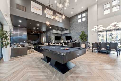 A pool table is in the middle of a room with a stone wall and a bar area. at The Laurel Apartments, Arizona  