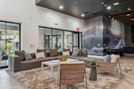 A modern living room with a grey sofa, a white coffee table, and a woven chair. at The Laurel Apartments, Arizona, 85286