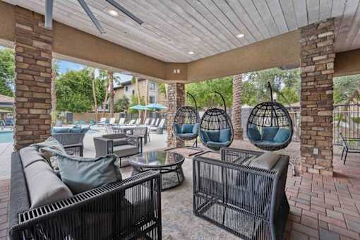 A patio with a black wicker chair and a table. at The Laurel Apartments, Arizona  