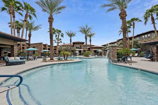 A swimming pool surrounded by palm trees and lounge chairs. at The Laurel Apartments, Chandler, 85286  