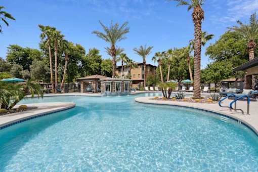 A large swimming pool surrounded by palm trees and lounge chairs. at The Laurel Apartments, Chandler  
