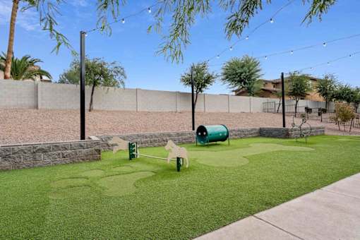 A small green lawn with a swing set and a green barrel. at The Laurel Apartments, Chandler  
