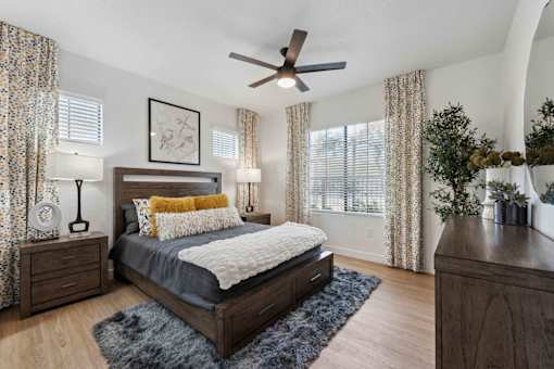 A bedroom with a bed, nightstands, and a ceiling fan. at The Laurel Apartments, Chandler, AZ  