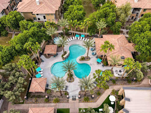 A pool surrounded by palm trees and a patio area. at The Laurel Apartments, Chandler, AZ 85286  