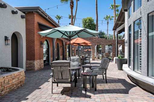 A patio with a table and chairs under an umbrella. at Lazo Apartment Homes, Arizona  