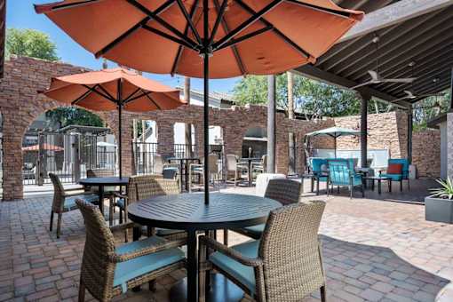 A patio with tables and chairs under umbrellas. at Lazo Apartment Homes, Arizona, 85225