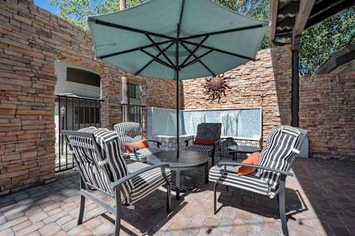 A patio with a table and chairs under an umbrella. at Lazo Apartment Homes, Chandler, AZ  