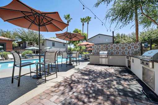 A poolside area with umbrellas and chairs. at Lazo Apartment Homes, Chandler, 85225  