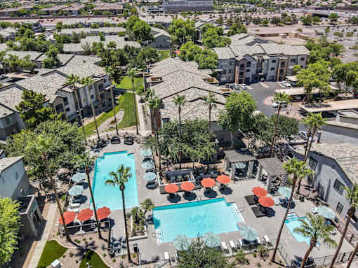 A pool surrounded by palm trees and umbrellas. at Lazo Apartment Homes, Arizona, 85225