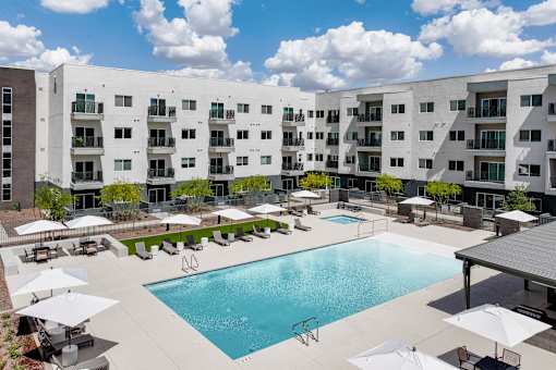 Resort style pool with sun deck and umbrellas at Lucero Apartments, Arizona, 85051